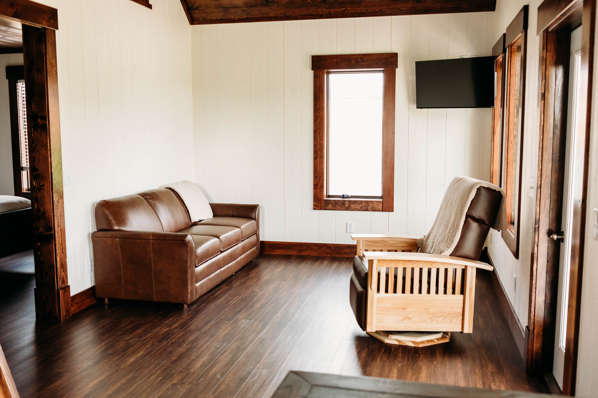 Inside the Villas at The VeNue. There is a brown leather queen sleeper sofa and brown leather and wooden rocking chair with a tan blanket folded over the back