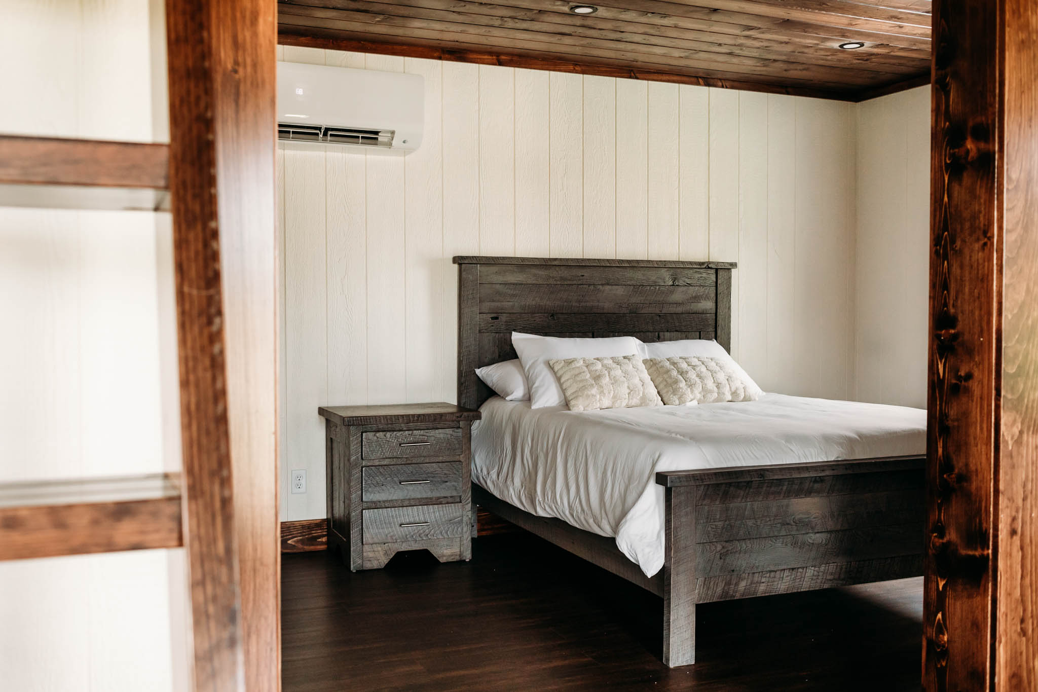 A view of the bedroom in the Villas at The VeNue. There is a wooden queen bed with white covers and a wooden nightstand