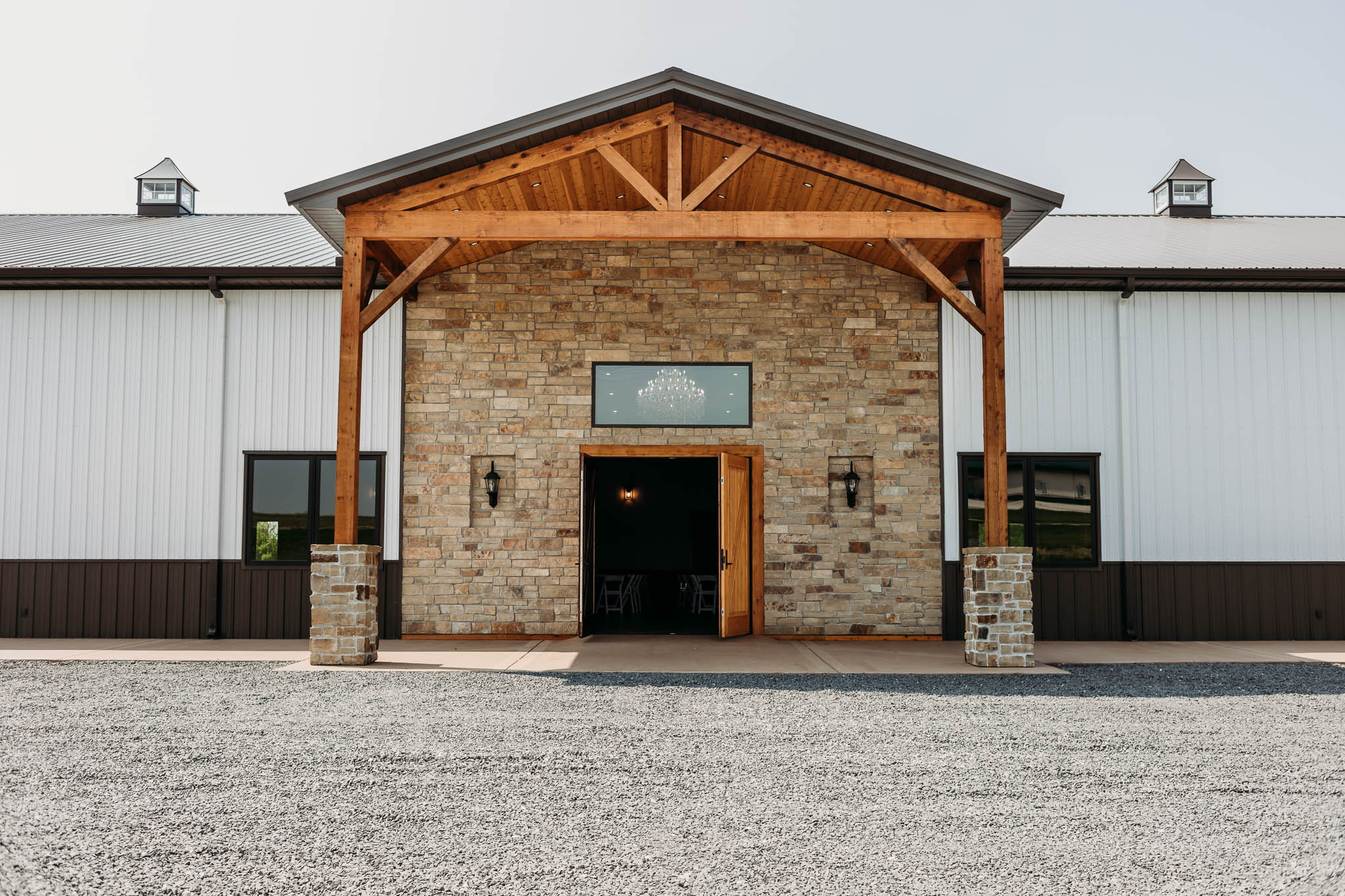 Front doors of The VeNue Event Space made of a large rock face with double-wide wood front doors. An awning hangs over the front door made of wood and black metal.