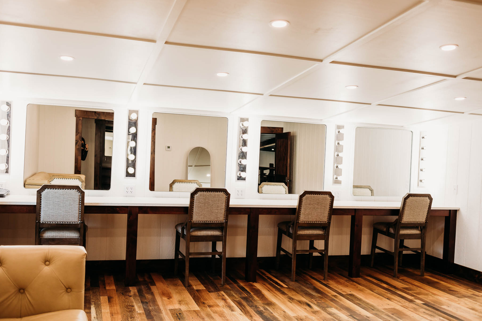 Bride's private getting ready suite at The VeNue Event Space features 4 large mirrors with vertical make up lights in between. There is a white granite make up counter that seats four.