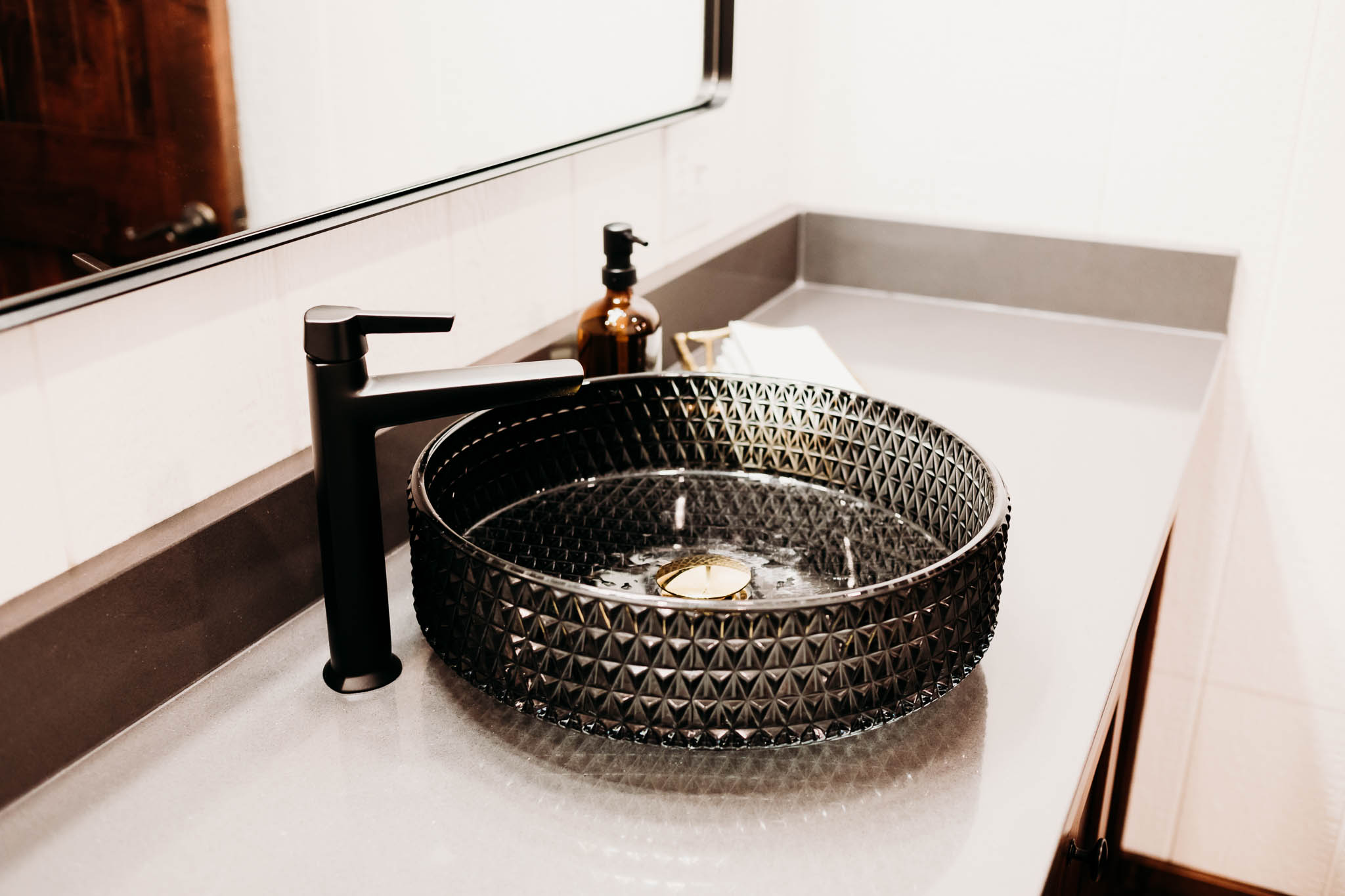 Black crystal bowl sink with flat black faucet in the private groom's suite restroom at The VeNue Event Space