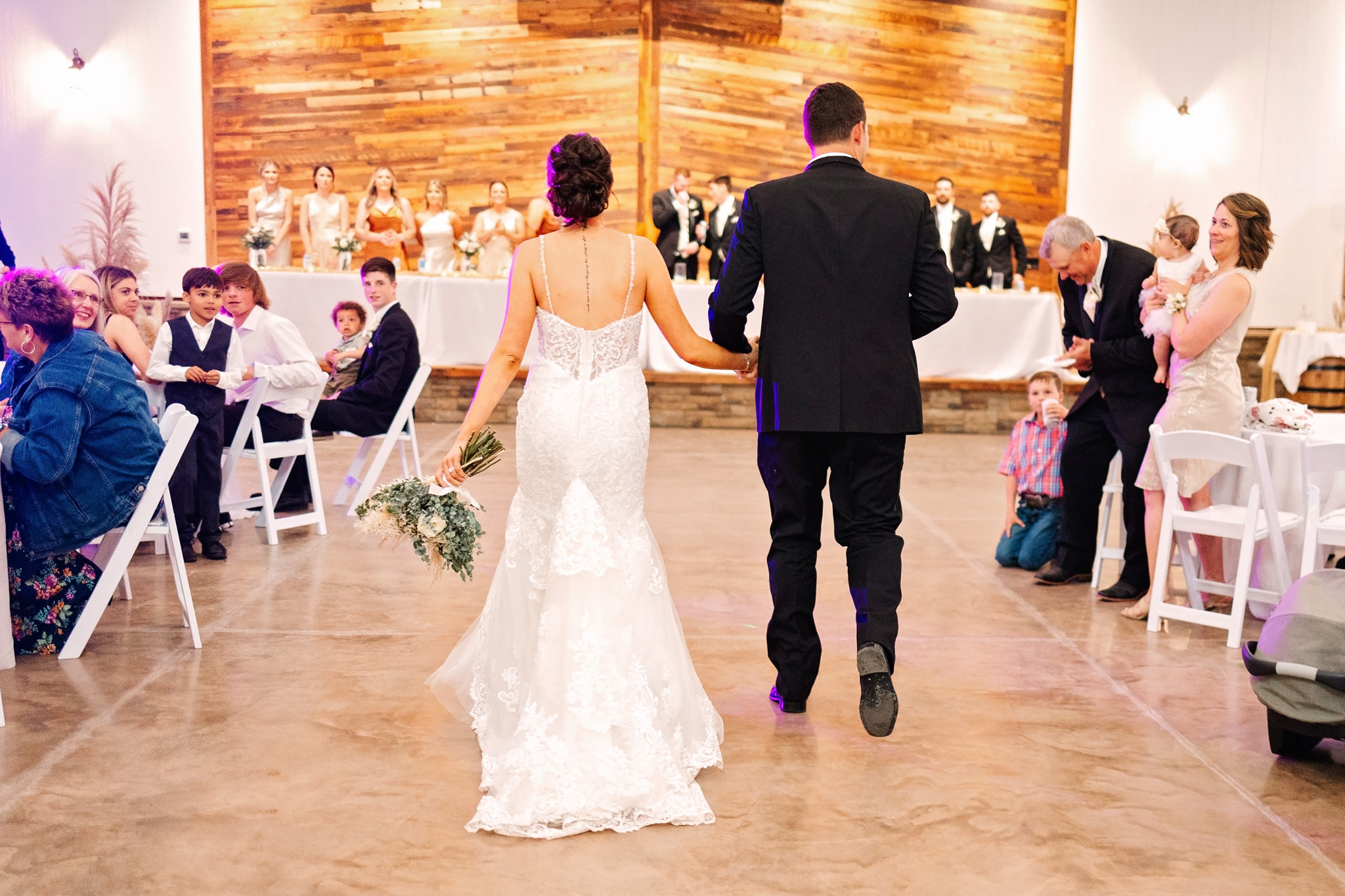 A bride and groom walk toward the stage at The VeNue Event Space