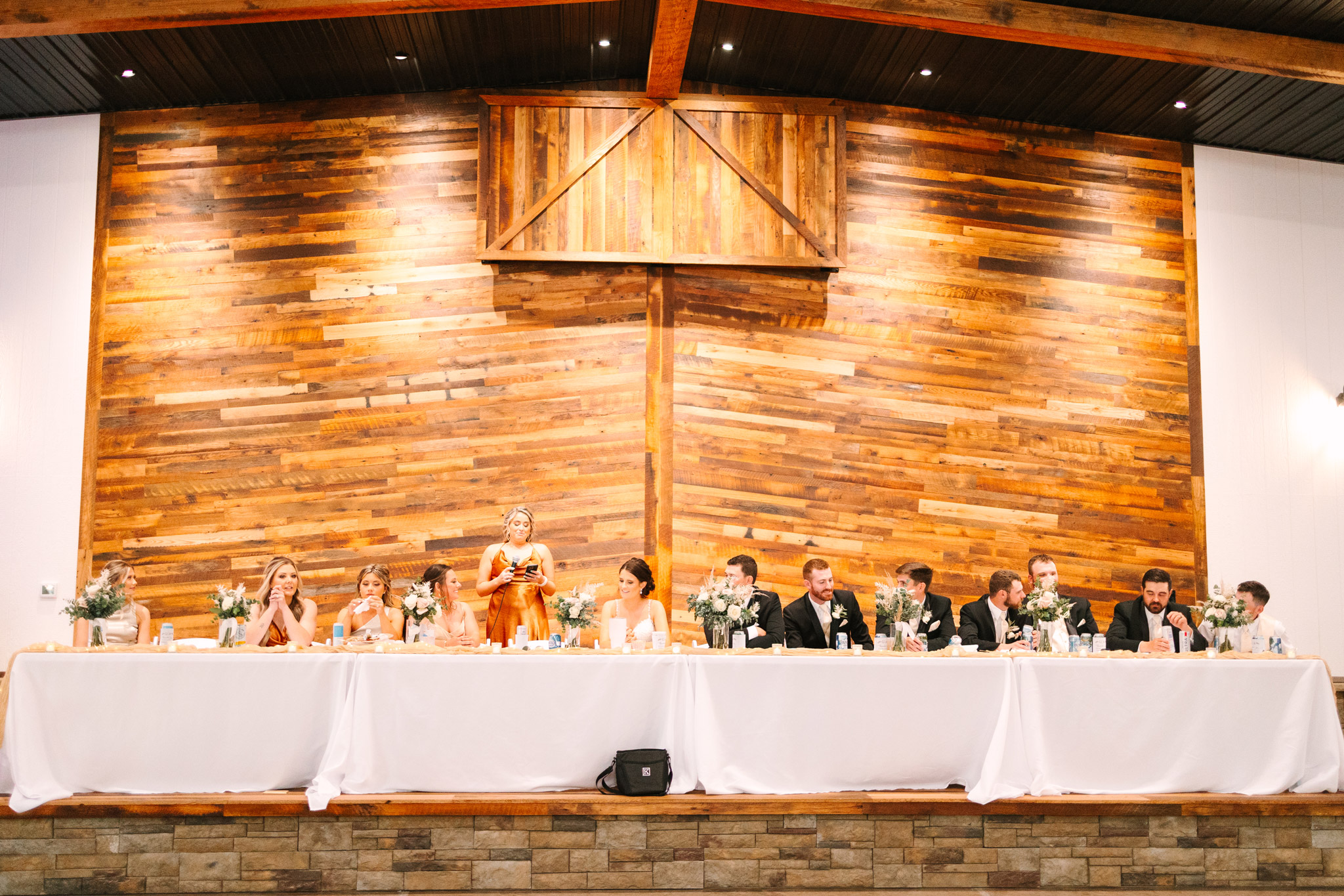 The 30 ft. stage at The VeNue Event Space with a large wedding party sitting a long, white table