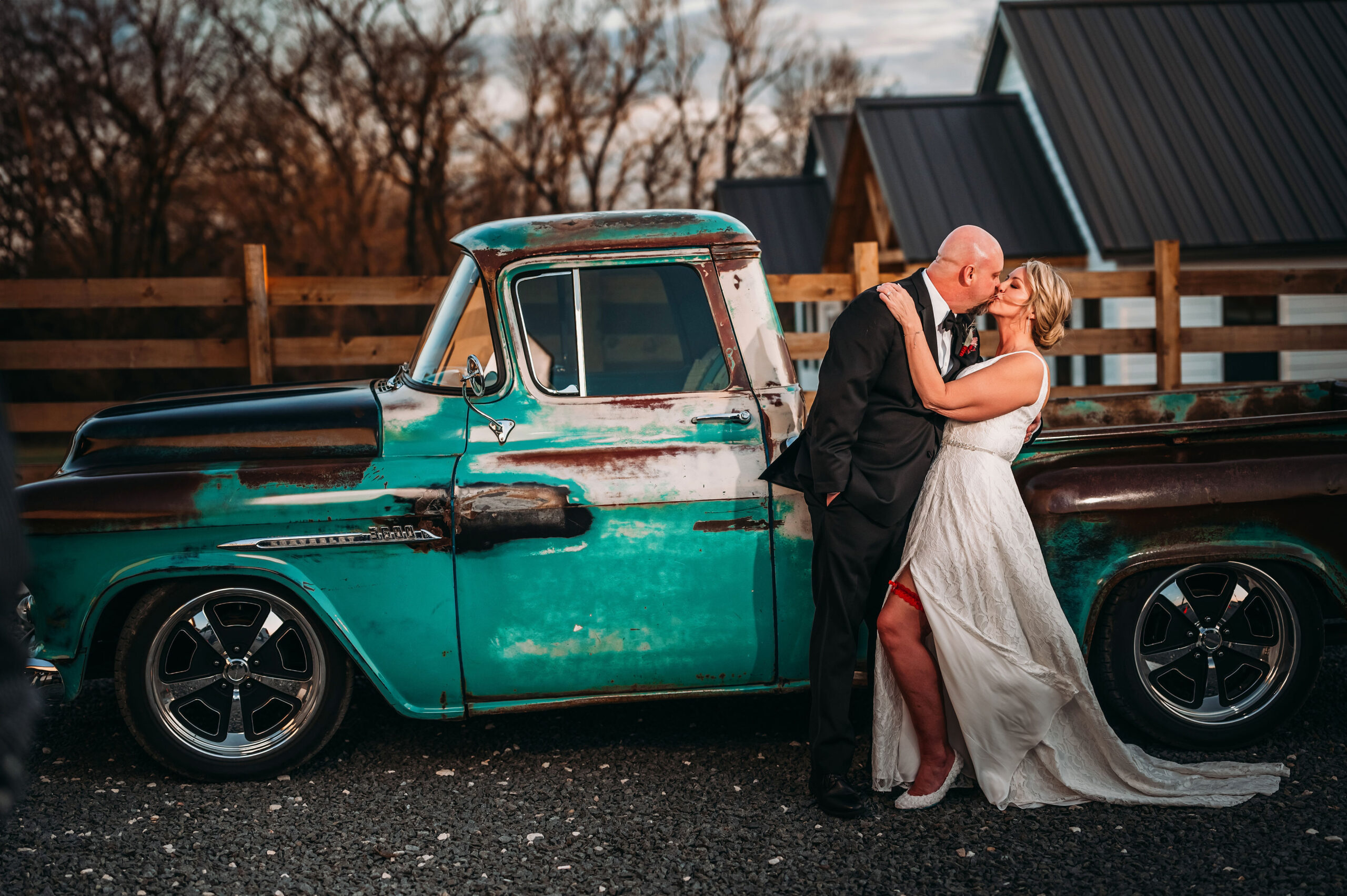 Bride and groom leaning against an old aqua colored truck in front of The VeNue Event Space